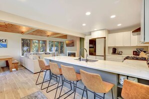 A modern kitchen with a central island, bar stools, and a built-in oven. - Bright & Stylish Girdwood Home- Ski, Bike, Explore (Anchorage)