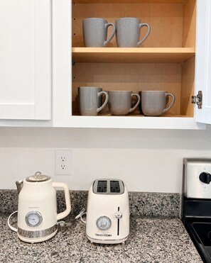 A kitchen with a white cabinet containing grey mugs, a white kettle, and a white toaster. - Kingsport Time Capsule - 3 bedrooms near  Eastman and Holston Valley hospital (Kingsport)
