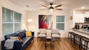 A modern living room with a sofa, armchairs, a coffee table, and a dining area with bar stools. - Kingsport Time Capsule - 3 bedrooms near  Eastman and Holston Valley hospital (Kingsport)