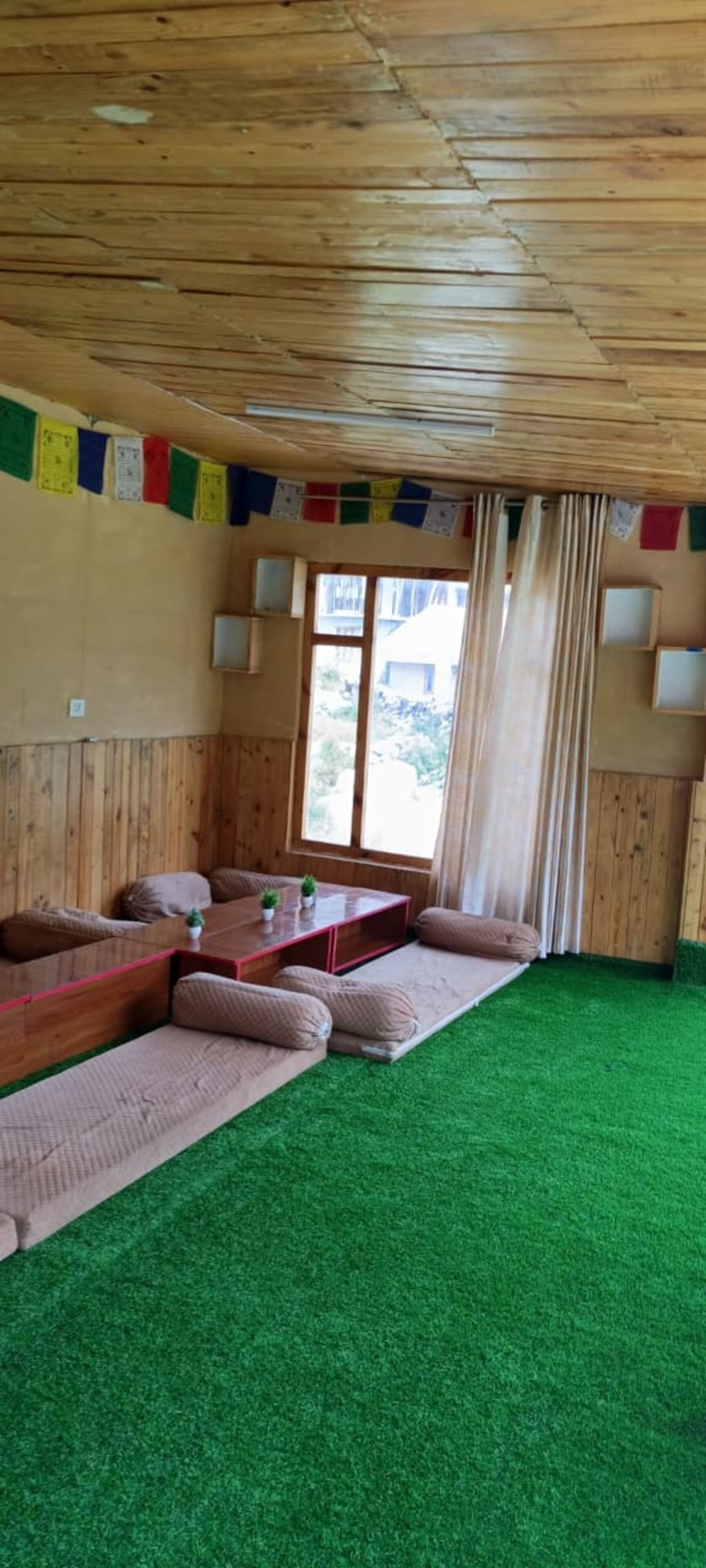 Ein Zimmer mit Holzboden, einer Couch-Garnitur, einem kleinen Tisch und einem Fenster mit Vorhängen.