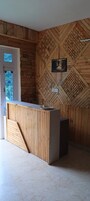 Una recepción con detalles de madera, un cuadro en la pared y una puerta que da a vistas de vegetación exterior.