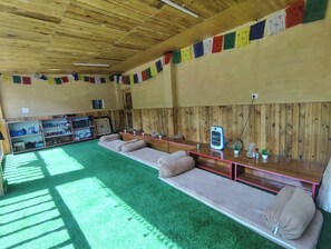 Una habitación con un largo banco, techo de madera y una pared con banderas coloridas.