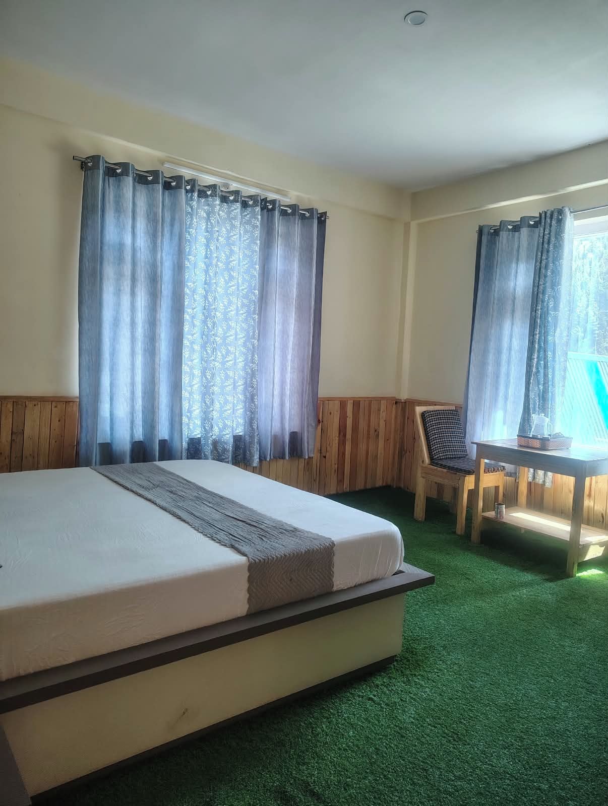 Una habitación con cama, una silla, una mesa y cortinas.