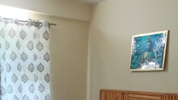 Una cama con cabecera de madera, almohadas grises y colchón blanco.