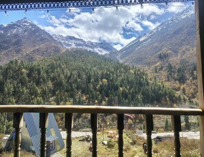 A mountain landscape with a view of a road and a building with a sloped roof. - Buddiez Space Hotel And Restaurant (Chitkul)