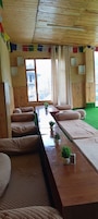 Una habitación con paredes y suelos de madera, una mesa larga con cojines, y vistas a un edificio.