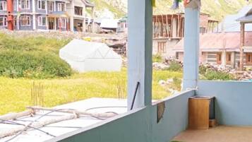 Una habitación con piso de césped artificial verde, pared blanca y ventana con vista a un edificio de múltiples ventanales.