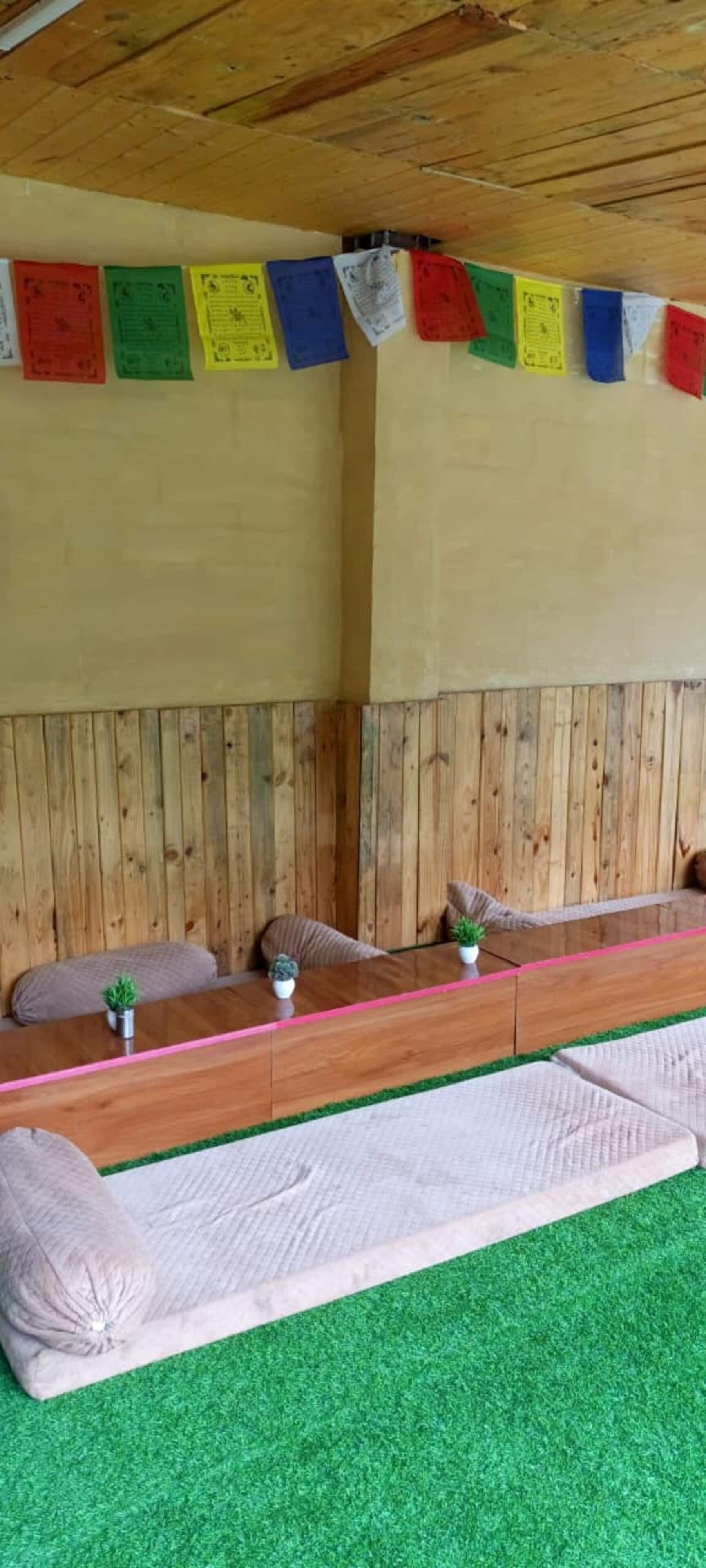 Una habitación con un banco de madera largo, césped artificial verde y una pared de madera con notas de papel de colores.
