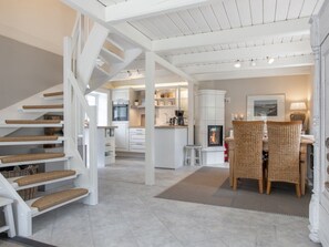 A modern interior with a staircase, kitchen, dining area, and fireplace. - Reetkate Sandwehle (Kirchspiel Garding)