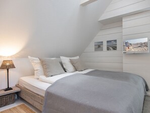 A bedroom with a bed, a lamp, and a wall-mounted TV. - Reetkate Sandwehle (Kirchspiel Garding)