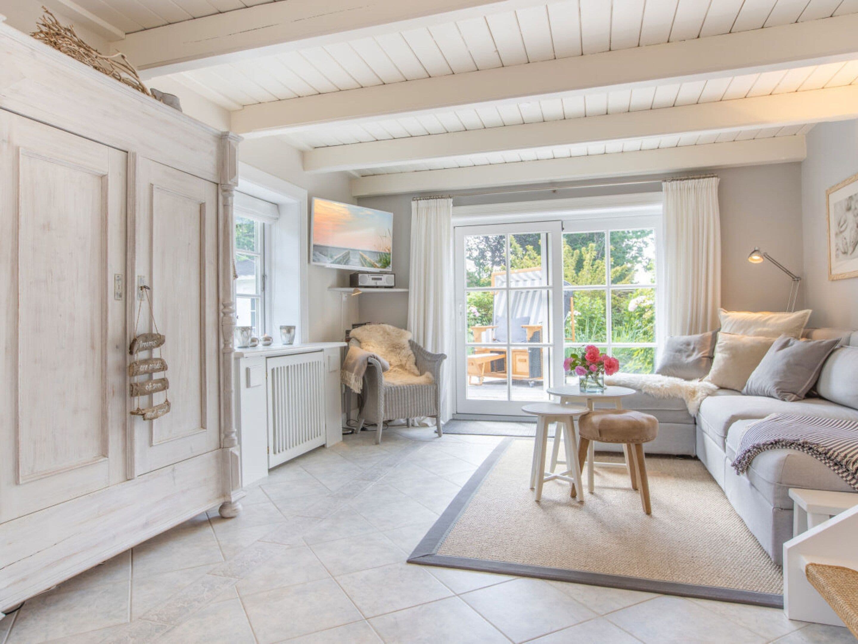A spacious room with a large window, a sofa, a chair, and a radiator.