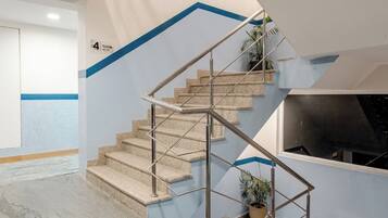 Una escalera moderna con barandales de metal, una planta en maceta y una pared de acento azul.