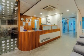 A reception desk with a wooden finish, a clock, and a sign that reads 'Cyber One'. - Royal orbit Hotel (Gurugram)