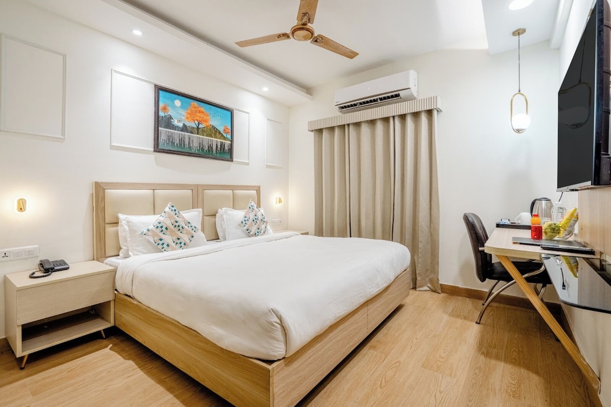Een hotelkamer met een bed, nachtkastje, bureau, stoel en een airconditioning.