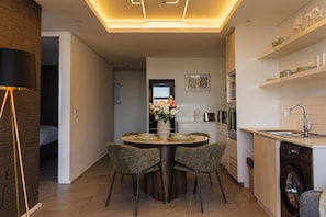 Cuina moderna amb zona de menjador, rentadora i lluminària de sostre.