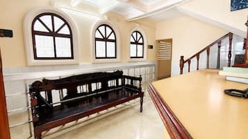 Un amplio vestíbulo con un banco de madera, una escalera y grandes ventanales de arco.