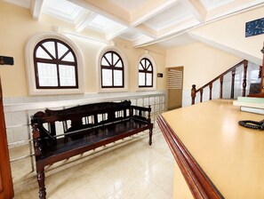 A spacious lobby with a wooden bench, a staircase, and large arched windows.