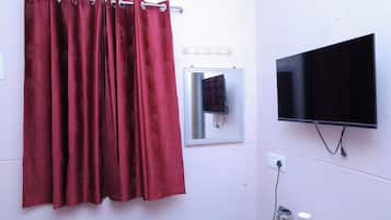 Un baño con cortina de ducha roja, televisor montado y una ventana pequeña.