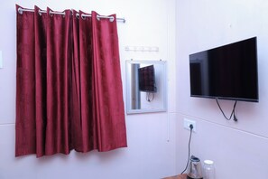 Un baño con cortina de ducha roja, televisor montado y una ventana pequeña.