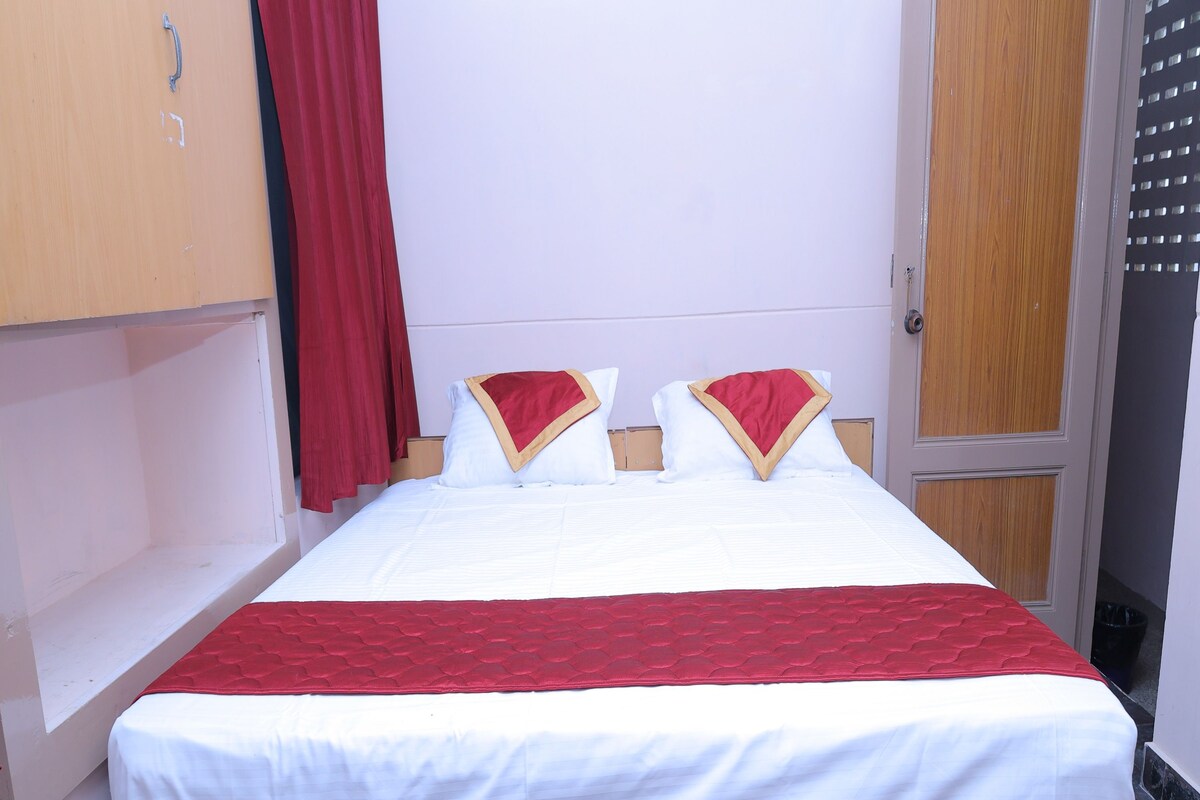 A single bed with a red and white bedspread, two wooden headboards, and a red curtain.