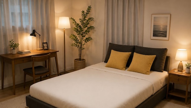 Un dormitorio ordenado con cama, mesitas de noche, un escritorio y una planta en maceta.