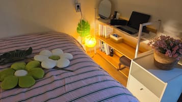 Un dormitorio ordenado con cama, mesita de noche, lámpara y escritorio con silla.