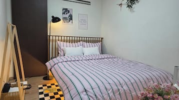 A bedroom with a bed, a standing lamp, a checkered rug, and wall art.