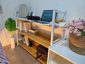 Un espacio de trabajo ordenado con una computadora portátil, libros y objetos decorativos en estanterías.