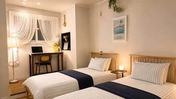 A hotel room with two beds, a desk, a chair, a lamp, and a framed picture on the wall. - Lumi House Itaewon (Seoul)