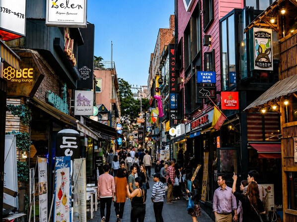 A bustling street lined with various shops and restaurants, including a dining lounge and a bar.