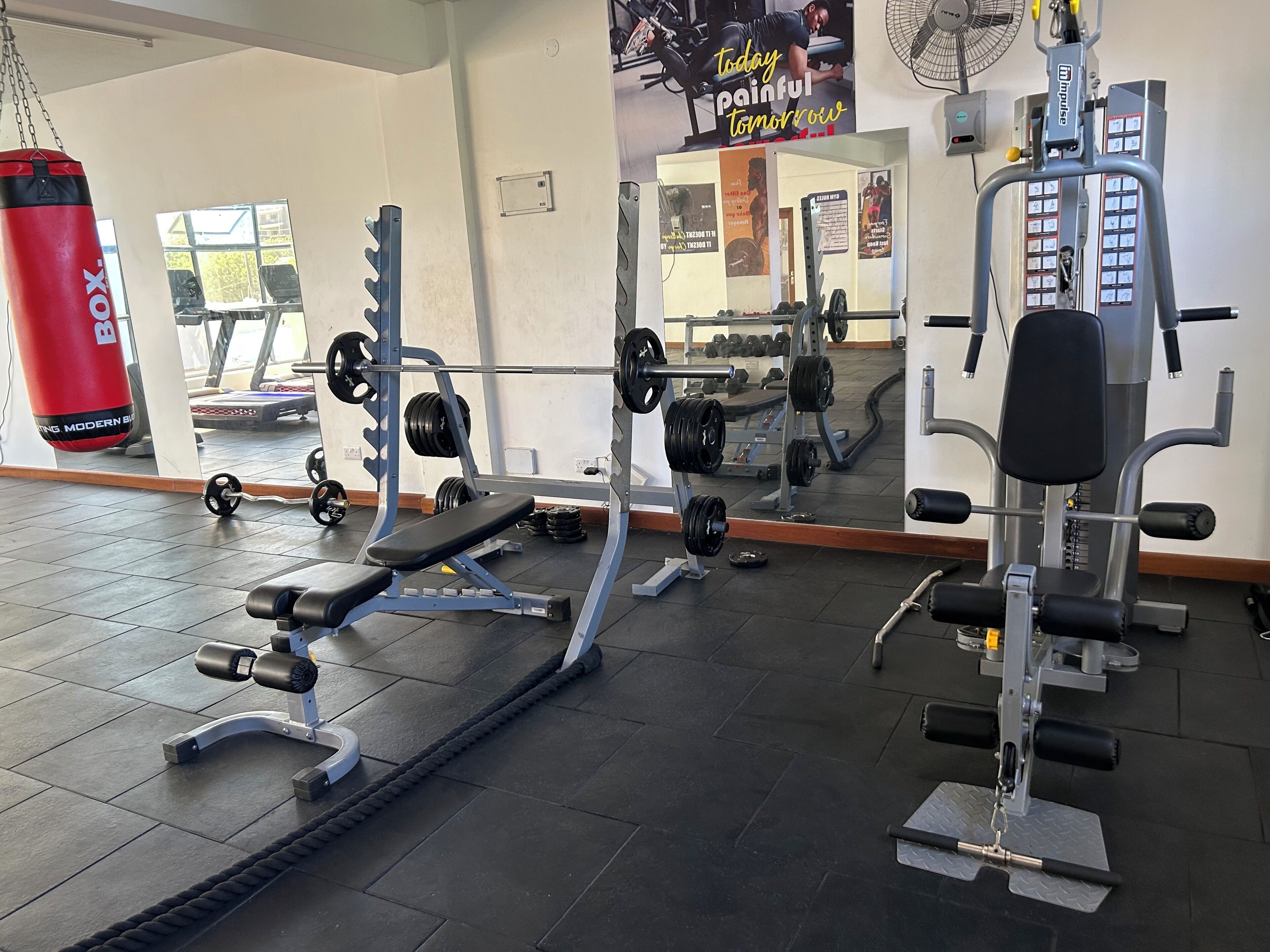 A gym with weightlifting equipment, a punching bag, and a mirror reflecting the space.