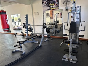 Una palestra con attrezzatura per sollevamento pesi, un sacco da boxe e uno specchio che riflette l'ambiente.