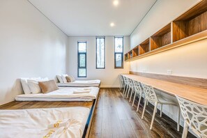 Ein modernes Zimmer mit zwei Betten, einem Holztisch und einer eingebauten Schrankwand.