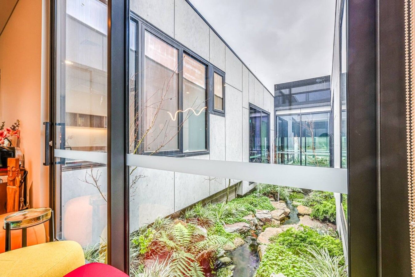 A modern building with large windows and a small garden area with rocks and plants.