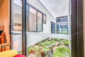 A modern building with large windows and a small garden area with rocks and plants. - StayAU Bulleen Urban Hideaway 5BR (Bulleen)