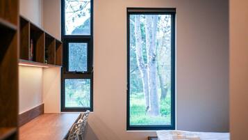 A room with a bed, a desk, and a window with a view of trees.