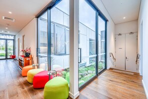 Ein modernes Interieur mit großen Fenstern, Holzböden und farbenfroher Sitzmöbel.