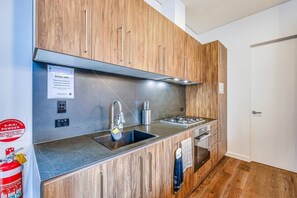 A modern kitchen with wooden cabinets, a stainless steel sink, and a built-in oven.