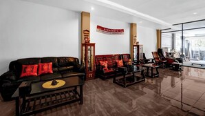 Eine moderne Lobby mit einer Ledersofa, Holzstühlen und einem Couchtisch. Ein Banner an der Wand zeigt 'DPR Republik Indonesien'.