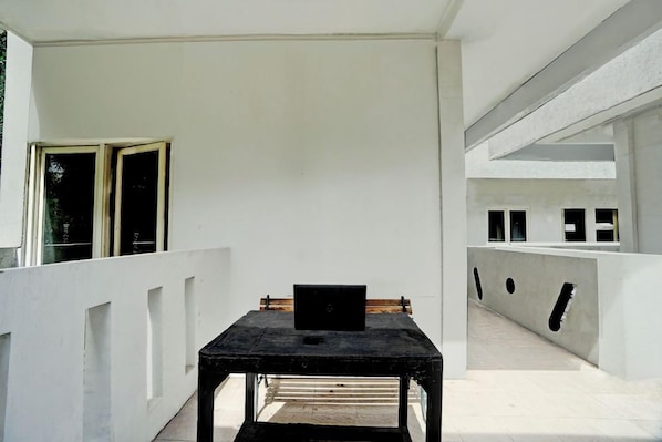 A room with a table and a laptop, a window, and a white wall. - Hotel O Near Ciputra World Surabaya Formerly Darmo Residence (Surabaya)