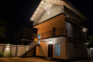 A multi-story residential building with a staircase leading to the upper floor, a balcony with railings, and a door with a window. - Casa Valley (Munnar)