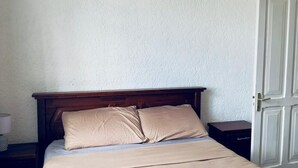 Un letto con testiera in legno, un comodino e una lampada da notte.