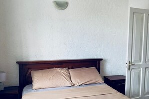 Una cama con cabecera de madera, una mesita de noche y una mesilla.