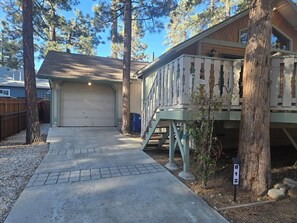 A residential property with a garage, a covered porch, and a driveway leading to the house. - Big Bear Cozy Cabin • Hot Tub • Family Friendly (Big Bear)