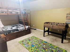A bunk bed with a ladder, a wooden table with a pegboard, a colorful play mat, and a wall with motivational stickers. - Big Bear Cozy Cabin • Hot Tub • Family Friendly (Big Bear)