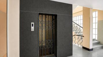 A modern elevator with a digital display and a metal grille door.
