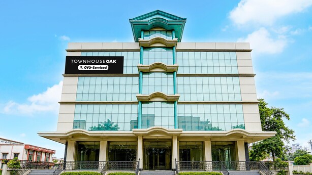 Un edificio a più piani con un cartello che riporta 'TOWNHOUSE OAK' e 'YO-Service'.