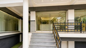 Una moderna scala con ringhiera in metallo, che conduce a un ingresso con porta in vetro.