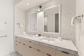 Ein modernes Badezimmer mit zwei Waschbecken, einem großen Spiegel und einem Handtuchhalter.