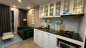 A compact kitchen with white cabinets, a black countertop, and a built-in oven.